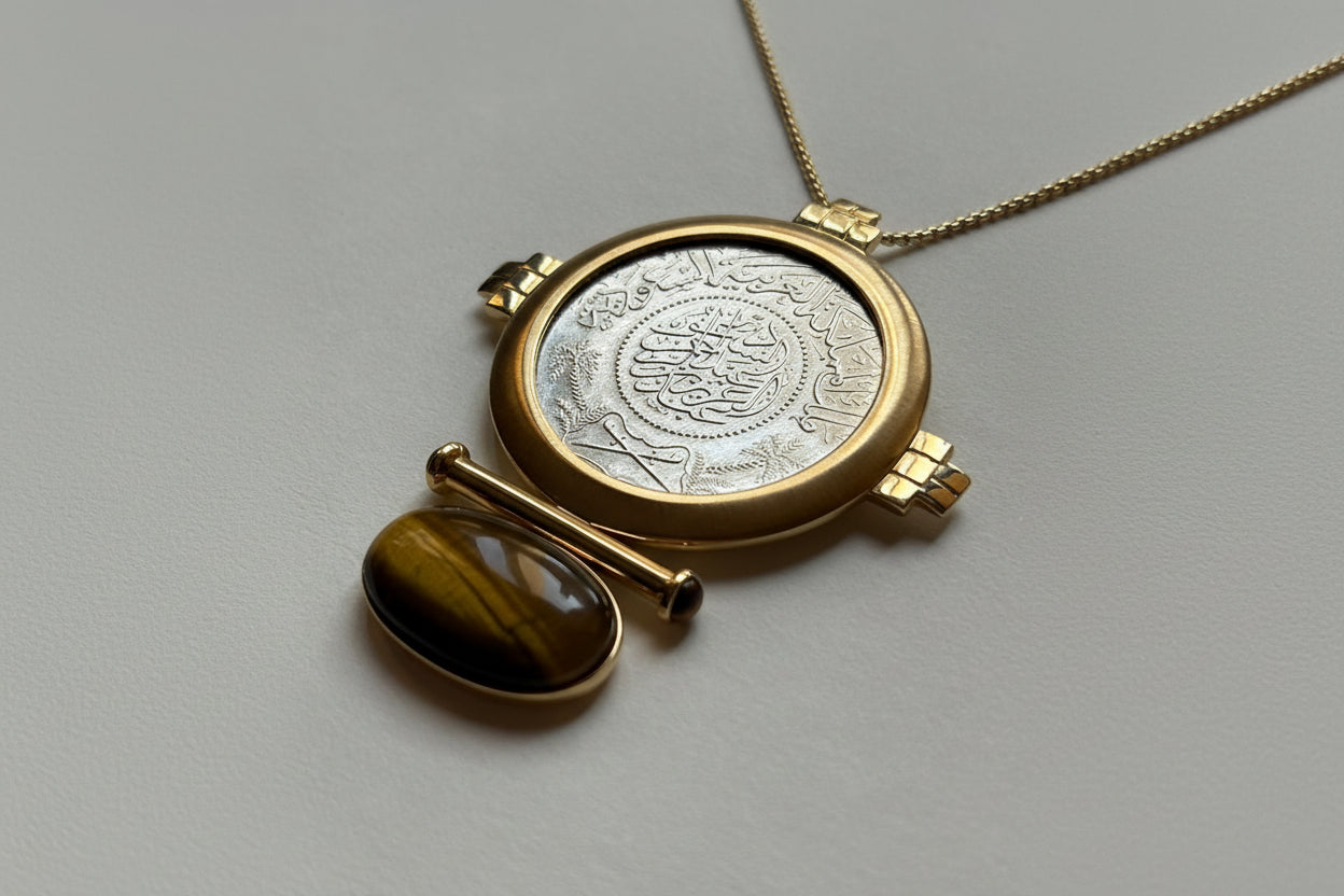 Gold pendant with a silver coin insert on a gray background