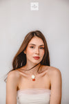 Woman wearing a necklace with a plain background and ULIA logo.