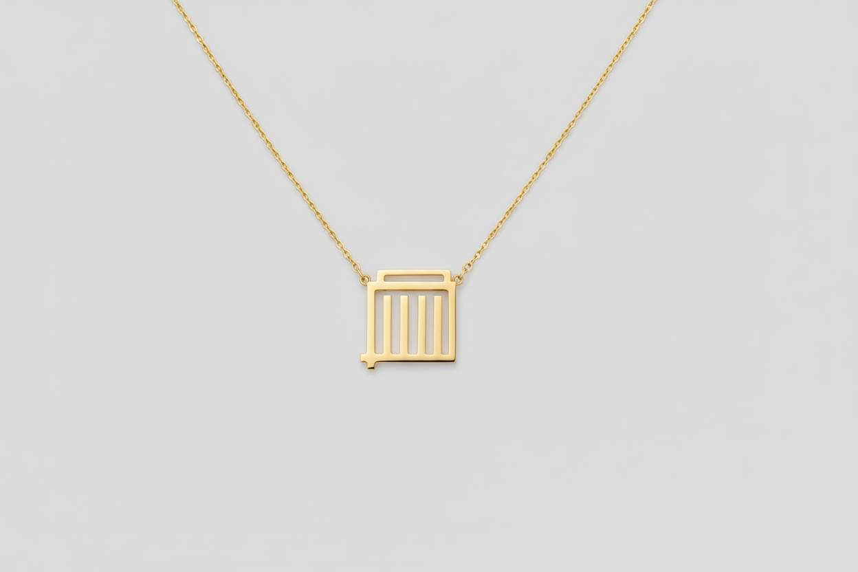 Gold necklace with a square pendant worn by a person against a neutral background